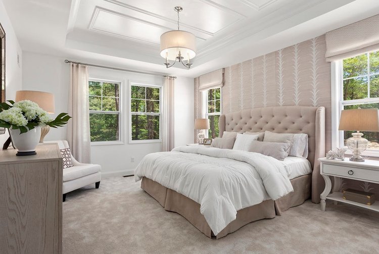 Master bedroom in model home with vaulted crown molding ceiling and cream/white finishes