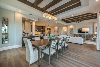 Model home dining, living, and kitchen area merchandised to accentuate exposed wood beams, open floor plan in Naples, FL.