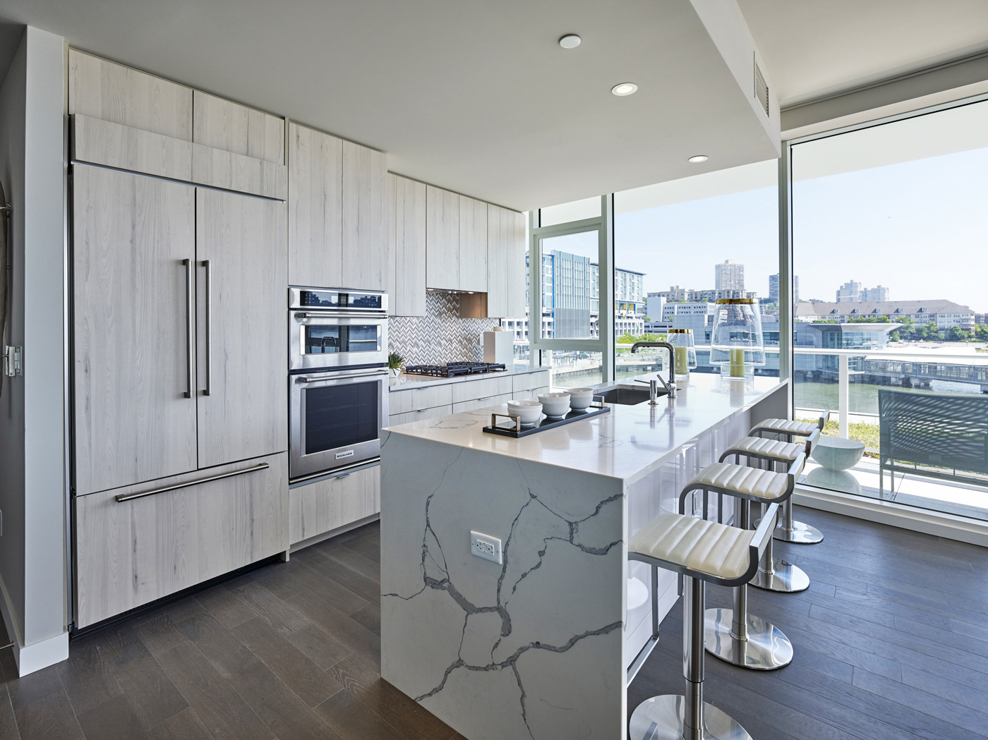 Modern white apartment kitchen merchandised with marble countertops and sleek countertops along with city views in New Jersey.