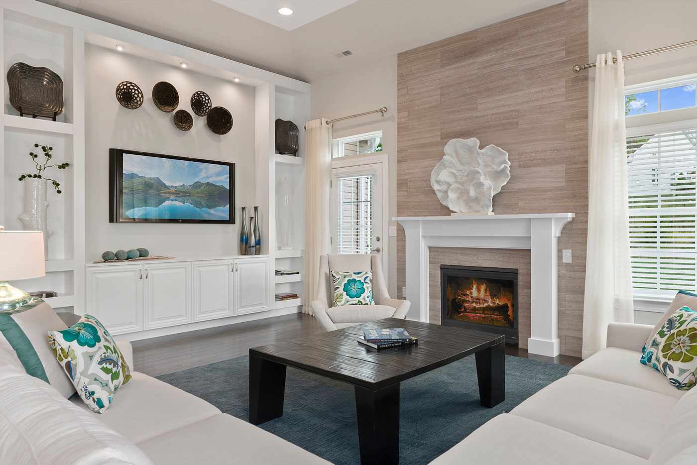 New Jersey model home featuring living room with classic white furniture, pops of blue and a wall length white built-in.