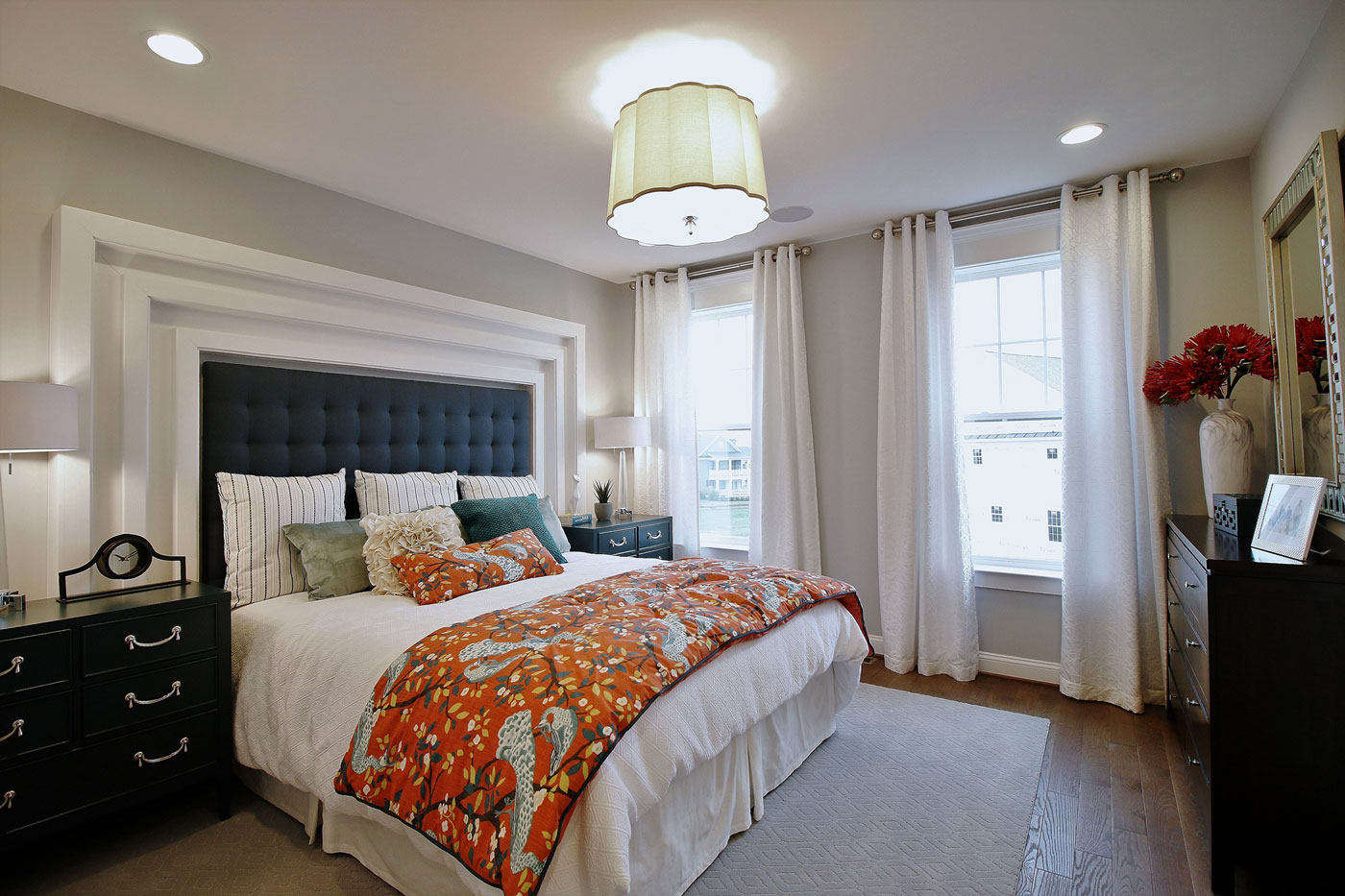 Maryland apartment master bedroom model merchandised with orange bedspread and dramatic upholstered headboard.