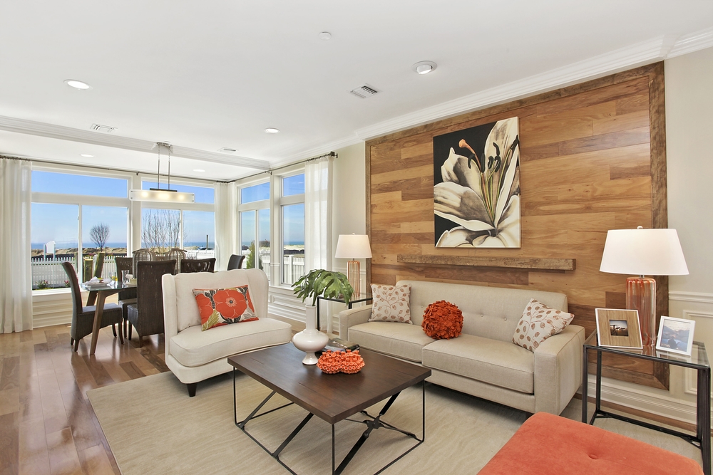 Single family living and dining room with neutral furnishings and wood panel feature wall