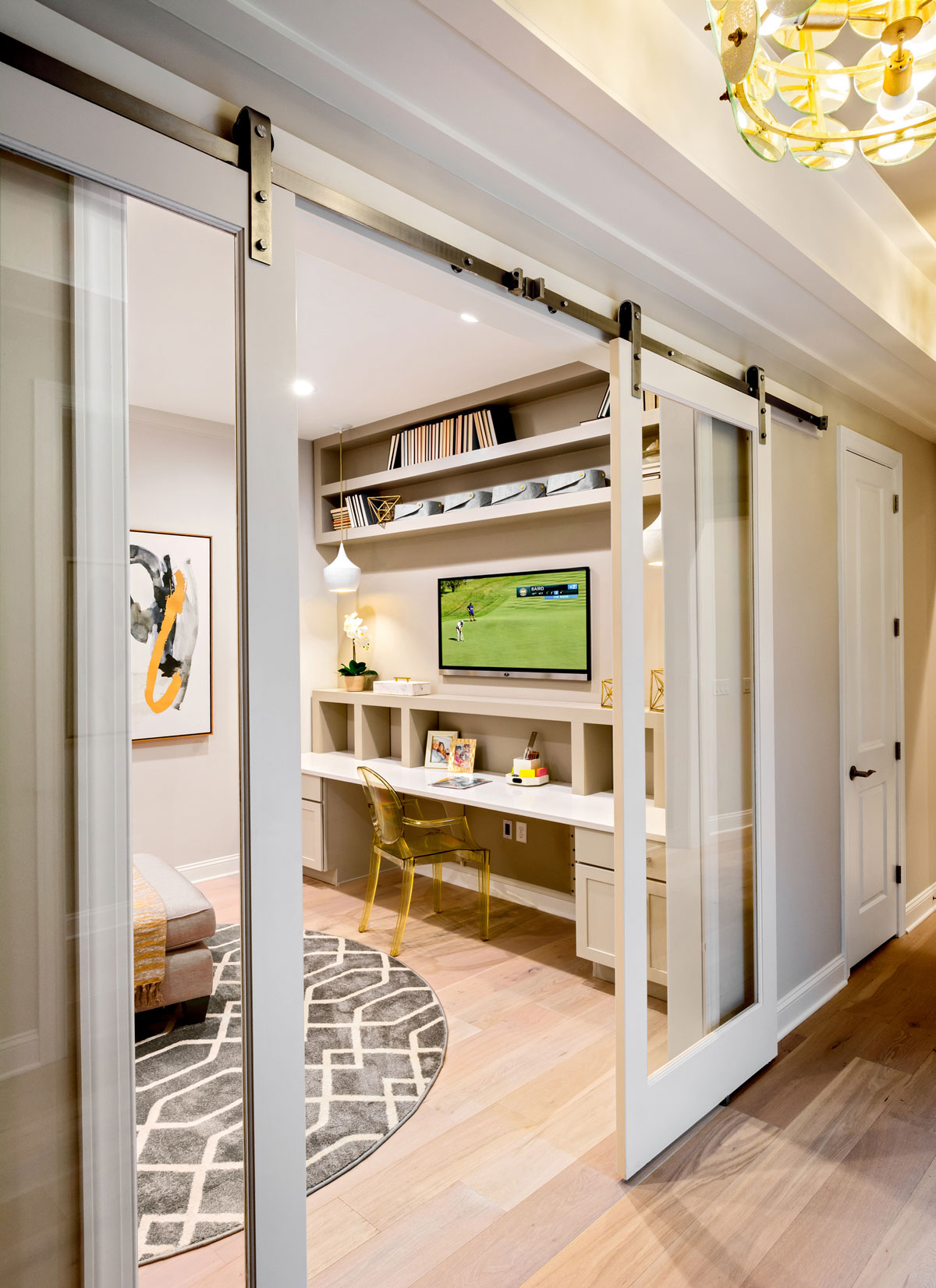 Creatively merchandised flex room with barn door, built-ins, and mobile furnishings in 55+ home buyer model in Delaware.