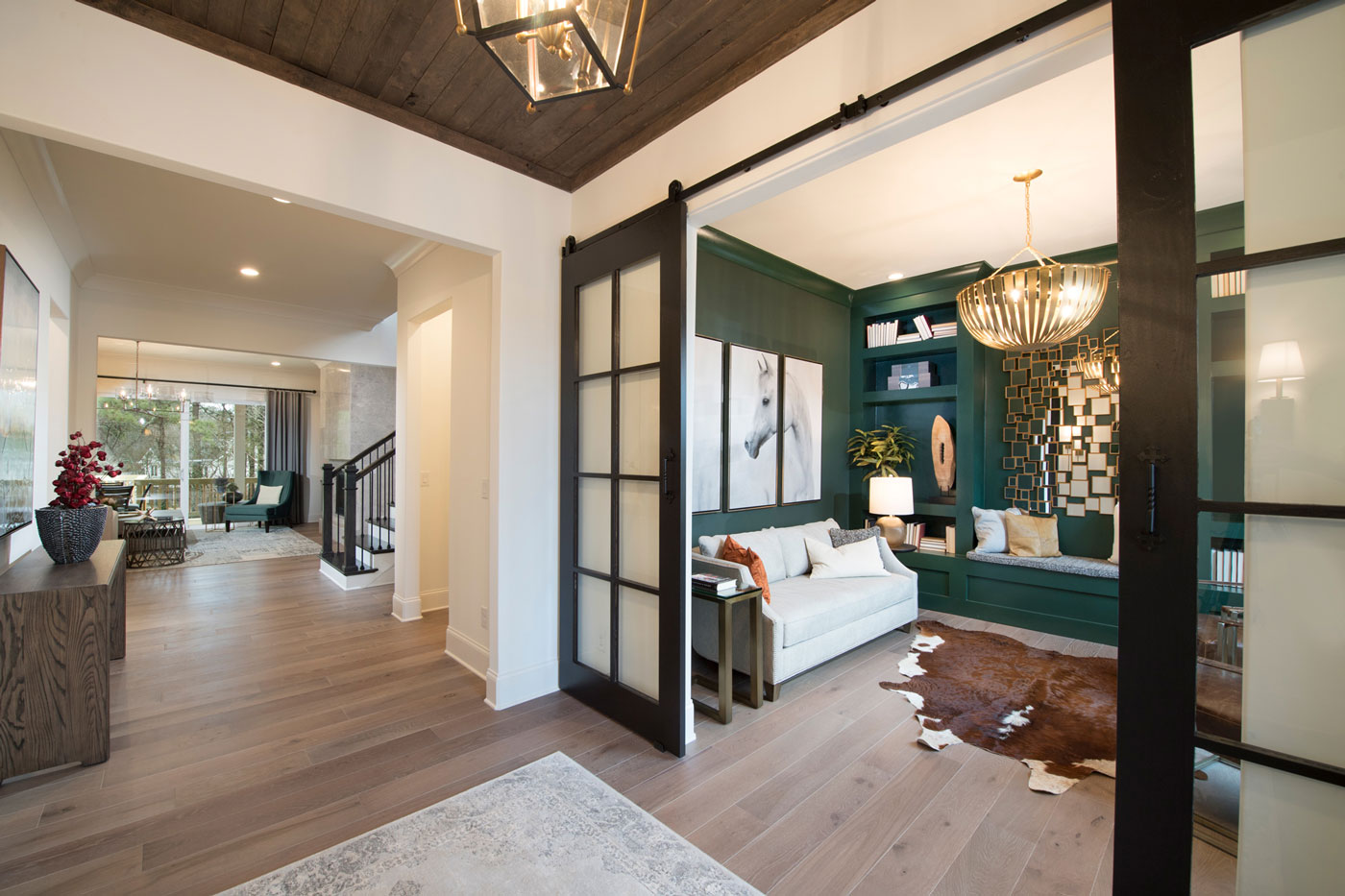 Georgia flex room designed with dark green walls, cow hide rug, horse picture, and contrasting finishes.