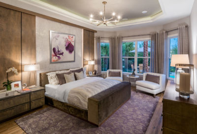 Master suite in award-winning 55+ model home merchandised with suede finishes, lighting designed to illuminate room, and purple accents in Florida.