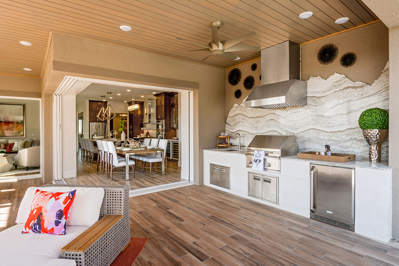 Outdoor kitchen with unique marble piece for backsplash, hardwood outdoor flooring, and lounge chairs in Florida.