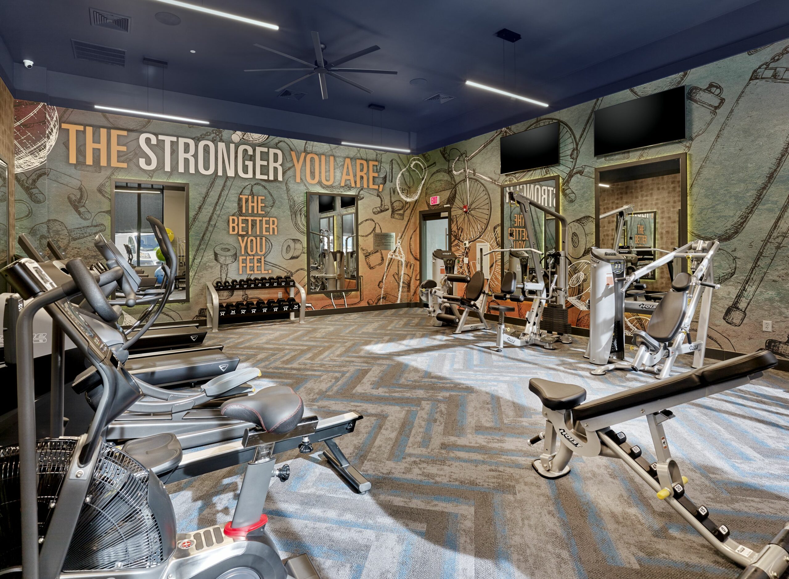 Fully equipped gym in upscale multifamily amenity space design.